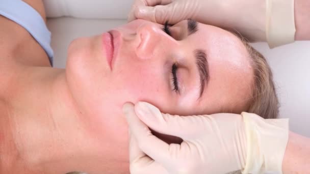 Hermosa chica tiene un masaje facial en una clínica de belleza. concepto cuidado de la piel, concepto de spa, tratamiento, masaje facial — Vídeos de Stock