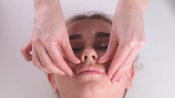 Masaje facial tratamiento de belleza. Primer plano de una cara de mujer joven acostada en la espalda, recibiendo masaje lifting facial, pellizcar y rodar técnica — Vídeos de Stock
