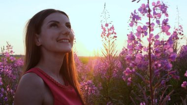 Gün batımında söğüt çayının içinde genç bir esmerin portresi. Parlak, güneşli bir akşamda, ateş otu saplı kız.