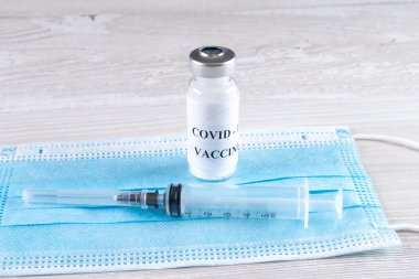 Koronavirüs aşısı, şırınga ve koruyucu maskeli şişeler. Bir salgın sırasında Corona virüsü tedavi konsepti, enjeksiyon, enjeksiyon ve klinik denemeler.