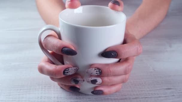 Beaux ongles manucurés sous la forme de bonbons au chocolat sur les mains féminines gros plan et une tasse de café. — Video