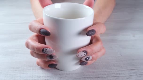 Mooie gemanicuurde nagels in de vorm van chocolade snoepjes op vrouwelijke handen close-up en een kopje koffie. — Stockvideo