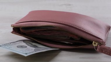 100 dolarlık banknot ve bir sürü parayla pembe cüzdan. Finans, harcamalar ve gelir kavramı 