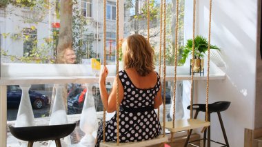 Kadın güneşli bir günde bir kafede salıncakta sallanıyor. Özgürlük kavramı, dilekleri gerçekleştirmek ve hayalleri gerçekleştirmek, üzüntü ve düşünce, geriye bakış: Sivastopol, Kırım - 17 Eylül