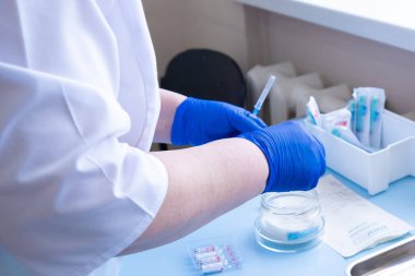 Bir doktorun elinde aşı ve şırıngayla dolu cam matara. Kapat..