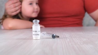 Doktorun ofisindeki küçük kız aşı olmuş. Covid-19 koronavirüs aşısı, grip, tehlikeli bulaşıcı hastalıklar için şırınga. Insanlarda ve çocuklarda yapılan klinik deneylerden sonra iğne