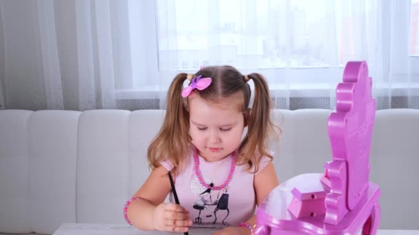 Niedliche kleine 3-jährige Mädchen in rosa Kleid und Perlen spielen mit Make-up vor dem Spiegel. — Stockvideo