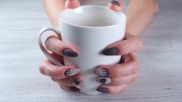 Piękne manicure paznokcie w postaci czekoladowych cukierków na kobiecych dłoniach zbliżenie i filiżankę kawy. — Wideo stockowe