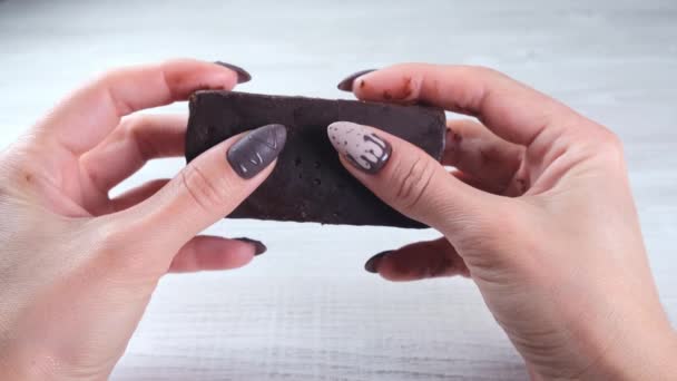 Kvinnliga händer med vackra manikyr naglar i form av choklad godis, bryta en vecklad bar av mörk choklad, närbild. Smaklig måltid. — Stockvideo