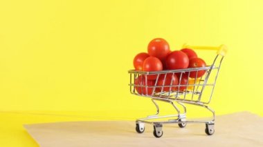 Sarı arka planda vişneli domatesli alışveriş arabası, yakın plan. Kara Cuma Alışveriş ve İndirim Konsepti