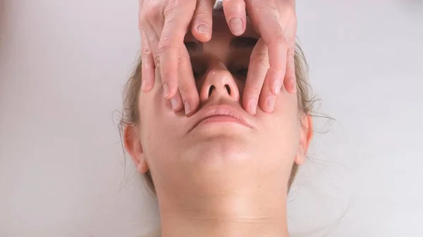 Massage facial soin de beauté. Gros plan d'une jeune femme visage couché sur le dos, se faire masser le visage levant, pincer et rouler technique — Photo