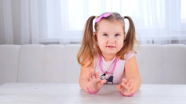 Portrait d'une jolie fille souriante de 3-4 ans avec de grands yeux et une belle coiffure avec un arc rose, enfant riant, perles et autres décorations. — Photo