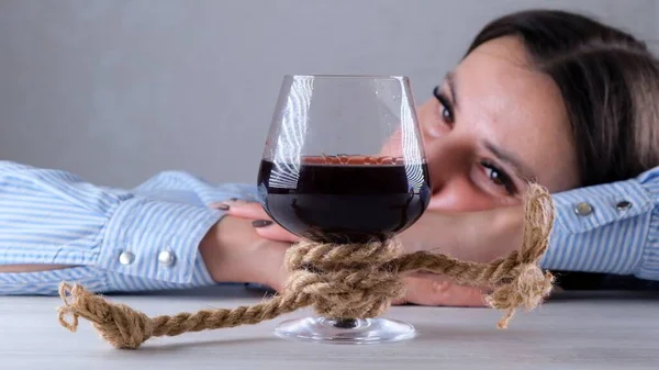 Triste mujer mirando copa de vino atado con cuerda de yute. El concepto de adicción al alcohol. El problema del tratamiento del alcoholismo — Foto de Stock