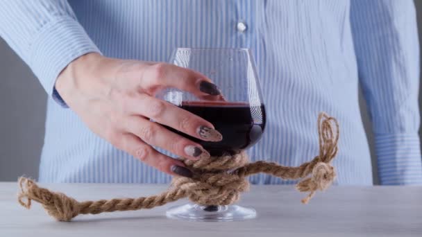 Şarap kadehi tutan kadın eli jüt bir iple bağlanmış. Alkol bağımlılığı kavramı. — Stok video