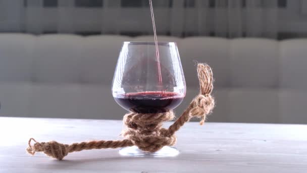 El vino se vierte en vidrio se ata con una cuerda. El concepto de dependencia del alcohol. — Vídeo de stock