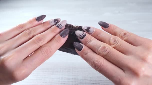 Kobiece dłonie z pięknymi paznokciami manicure w postaci czekoladowych cukierków, łamiąc rozłożony batonik ciemnej czekolady, zbliżenie. Smacznego.. — Wideo stockowe