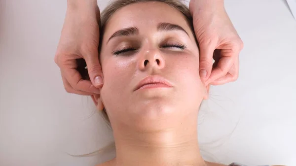 Bella ragazza ha un massaggio facciale in una clinica di bellezza. concetto cura della pelle, concetto di spa, trattamento, massaggio facciale — Foto Stock