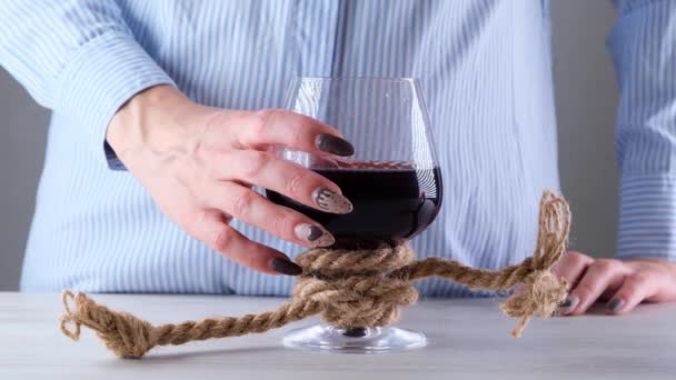 Vrouwelijke hand heft wijnglas wordt gebonden met een jute touw. Het begrip alcoholverslaving. — Stockvideo