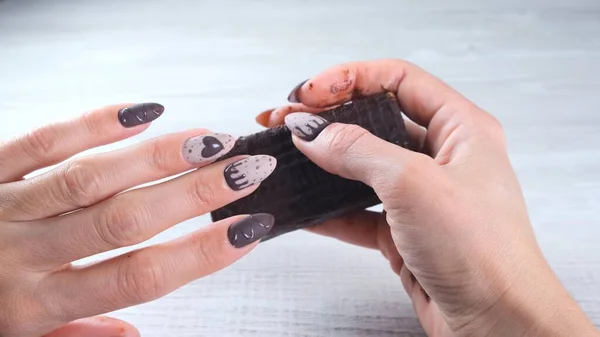 Kobiece dłonie z pięknymi brązowymi paznokciami manicure w postaci czekoladowych cukierków, trzymając rozłożony batonik ciemnej czekolady, zbliżenie. Smacznego.. — Zdjęcie stockowe