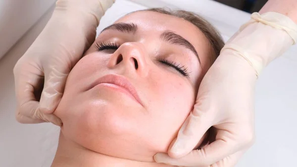 Hermosa chica tiene un masaje facial en una clínica de belleza. concepto cuidado de la piel, concepto de spa, tratamiento, masaje facial — Foto de Stock