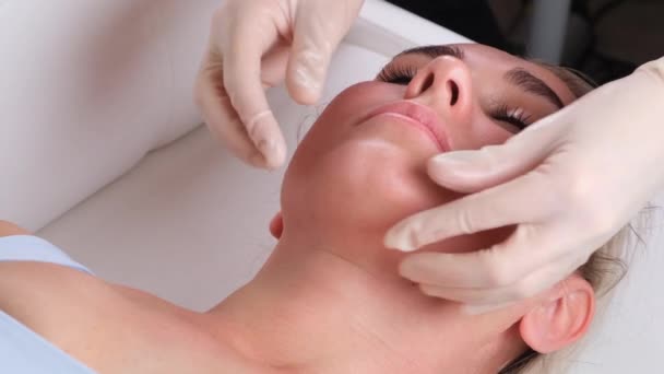 Massage du menton de femme jeune femme pendant le massage du visage au salon de beauté — Video