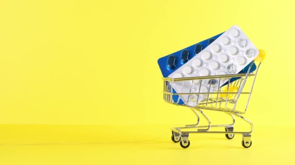 Warenkorb mit Pillen auf gelbem Hintergrund, Nahaufnahme. Medizinkonzept, Online-Shopping — Stockvideo