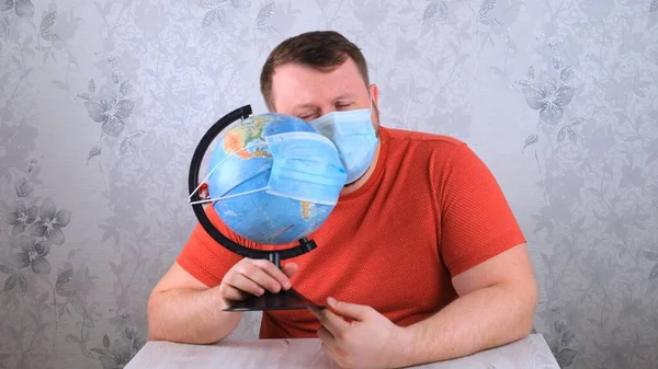 Muž je smutný kvůli chorobám na plánu a nedostatku cestování. samec vypadá v ochranné masce a pandemické vakcíně globálně. Koncepce léčby koronového viru, injekce, klinické studie — Stock fotografie
