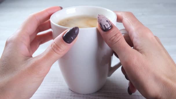 Hermosas uñas cuidadas en forma de caramelos de chocolate en las manos femeninas de cerca y una taza de café. — Vídeos de Stock