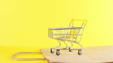 Sarı arka planda boş bir alışveriş arabası, yakın plan. Kara Cuma Alışveriş ve İndirim Konsepti