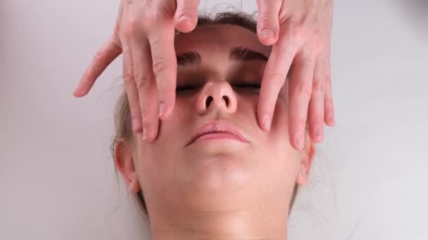 Massage facial soin de beauté. Gros plan d'une jeune femme visage couché sur le dos, se faire masser le visage levant, pincer et rouler technique — Video