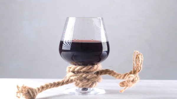 La copa de vino está atada con una cuerda. El concepto de dependencia del alcohol. — Foto de Stock