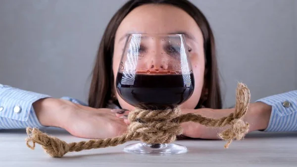 Ledsna kvinnliga ser vinglas bundna med jute rep. Begreppet alkoholmissbruk. Problemet med alkoholism — Stockfoto