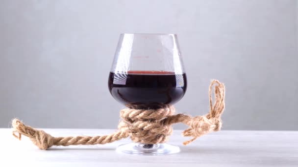Sklenice na víno je přivázaná provazem. Koncept závislosti na alkoholu. — Stock video