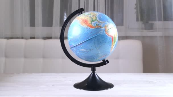 Model globusu se otáčí na dřevěném stole. Bílá zeď prázdný prostor pozadí: Moskva, Rusko - Únor 25, 2021