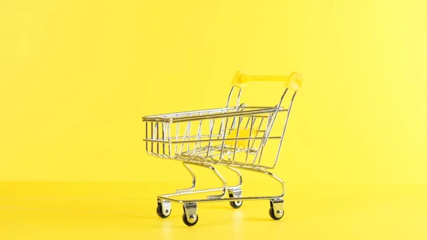 Vacío carrito de compras sobre un fondo amarillo, primer plano. Viernes Negro Compras y descuento Concepto — Foto de Stock