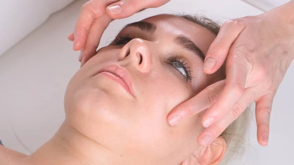Hermosa chica tiene un masaje facial en una clínica de belleza. concepto cuidado de la piel, concepto de spa, tratamiento, masaje facial —  Fotos de Stock