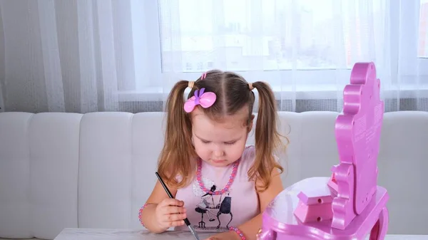 ピンクのドレス姿の可愛い3歳の女の子と鏡の前で化粧で遊んでいるビーズ. — ストック写真