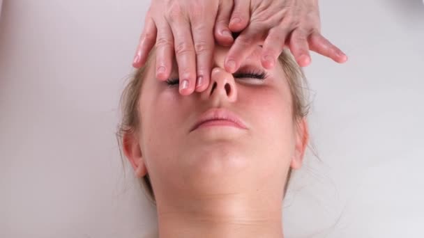 Gesichtsmassage Schönheitsbehandlung. Nahaufnahme eines jungen Frauengesichts auf dem Rücken liegend, Gesichtsstraffung Massage, Quetsch- und Rolltechnik — Stockvideo