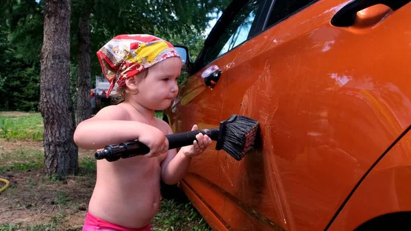 Mixen grap Kleine meid helpt om te doen Handmatig carwash met water onder druk in de auto wassen buiten in de zomer. — Stockfoto