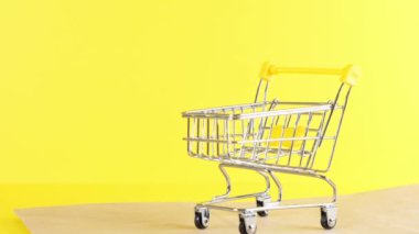 Sarı arka planda boş bir alışveriş arabası, yakın plan. Kara Cuma Alışveriş ve İndirim Konsepti