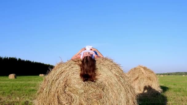 Young female lies on a haystack and throws his hat. Rural area. freedom concept — Stock Video