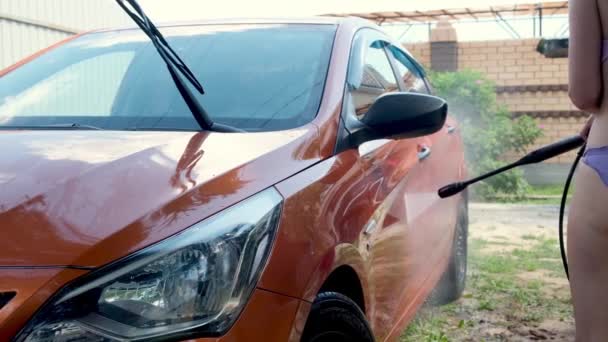 Mezcla broma niña ayuda a mamá a hacer manual de lavado de coches con agua a presión en el lavado de coches al aire libre en verano. — Vídeo de stock