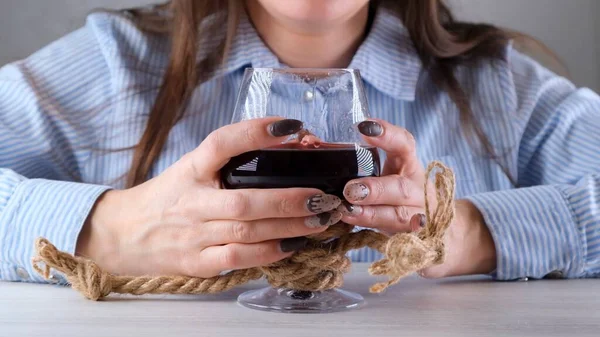 Ręce samicy trzymającej kieliszek do wina przywiązane są jałową liną. Koncepcja uzależnienia od alkoholu. Problem leczenia alkoholizmu — Zdjęcie stockowe