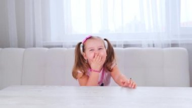 3-4 yaşlarında güzel bir kızın portresi. Büyük gözleri ve güzel bir saç stili var. Pembe bir fiyonk, gülen çocuk, boncuklar ve diğer süslemeler..