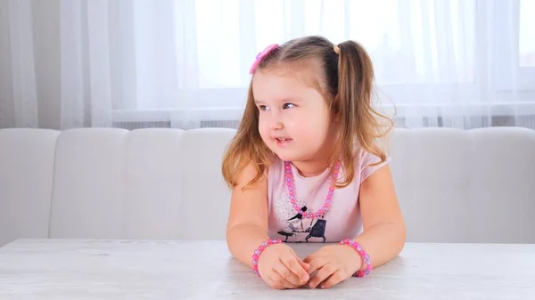 Portrait d'une jolie fille de couvée mignonne de 3-4 ans avec de grands yeux et une belle coiffure avec un arc rose, enfant riant, perles et autres décorations. — Photo