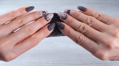 Çikolata şeklinde güzel manikür tırnakları olan bir kadın eli. Elinde dürülmemiş koyu çikolatalı bir çubuk var. Yakın plan. Afiyet olsun..