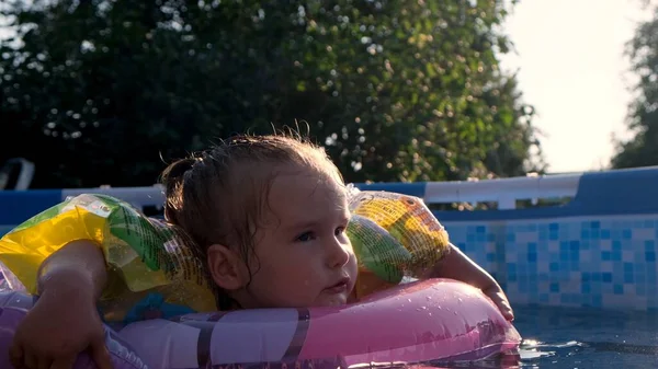 女の子は裏庭のプールで膨脹可能なリングで泳ぐ: Tyumen, Russia - 2020年5月12日. — ストック写真