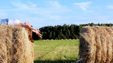 Genç dişi bir samanlıkta yatıyor ve şapkasını fırlatıyor. Kırsal bölge. özgürlük kavramı