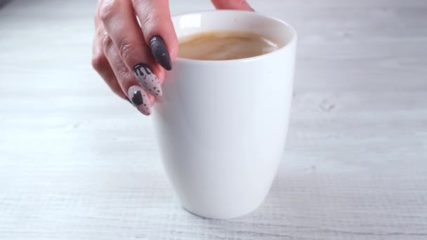 女性の手にチョコレートキャンディーの形で美しいマニキュア爪を閉じるとコーヒーカップ. — ストック動画