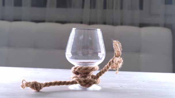 Le verre à vin vide est attaché avec une corde de jute. Le concept de dépendance à l'alcool. — Video